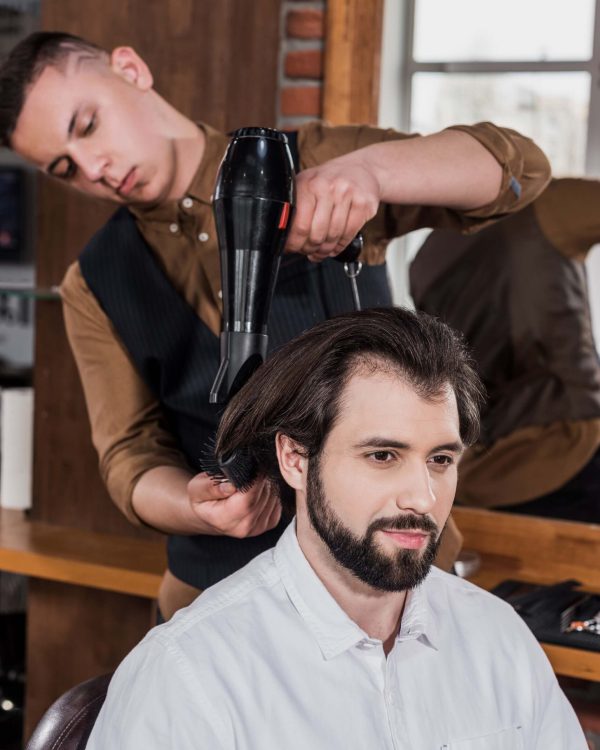 serious-barber-combing-hair-of-customer-with-haird-K3HGKNC.jpg